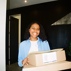 Commerçante souriante tenant un colis dans sa boutique