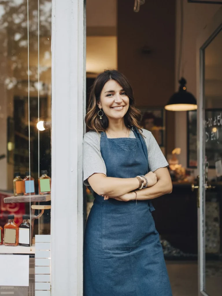 Commerçante souriante devant la vitrine de sa boutique