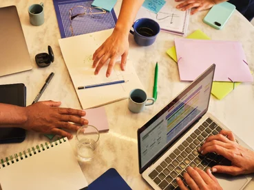 Équipe réunie autour d’une table avec un ordinateur portable et des carnets