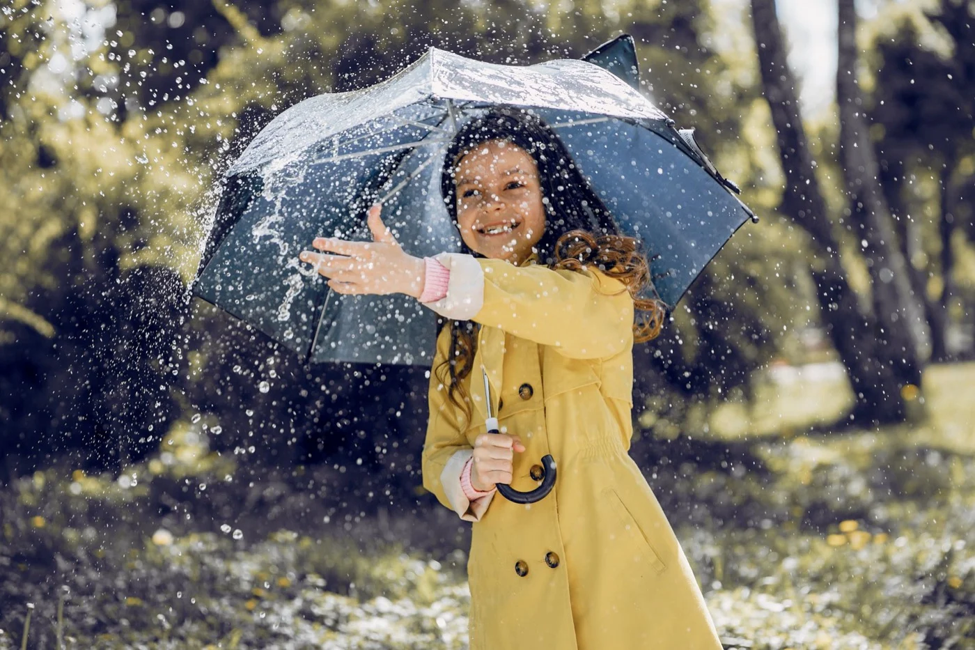 Enfant en imperméable jaune sous un parapluie, un jour de pluie