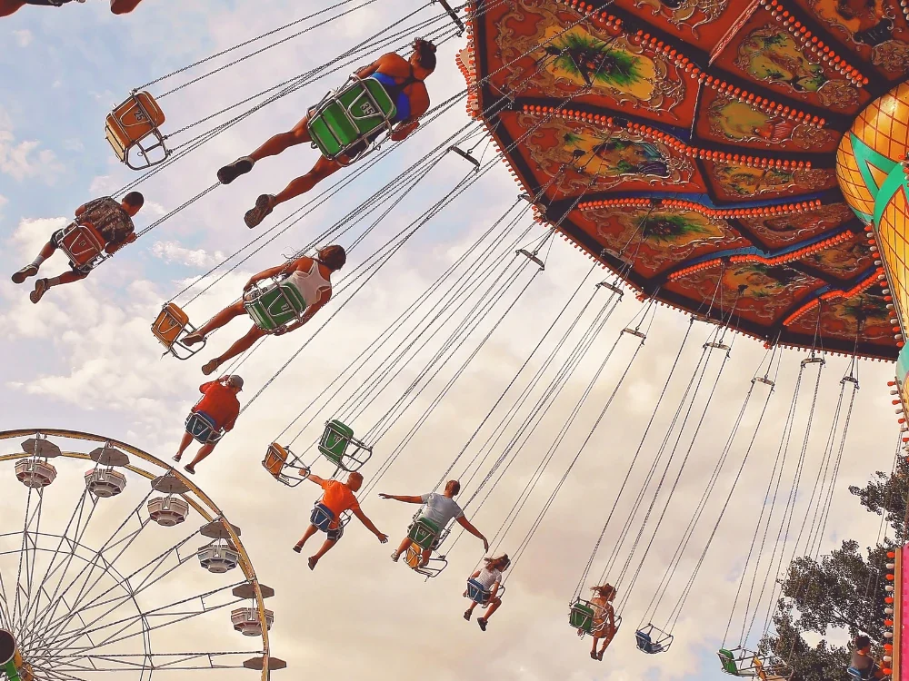 Chaises volantes et grande roue d’un parc de loisirs vues en contre-plongée au coucher du soleil
