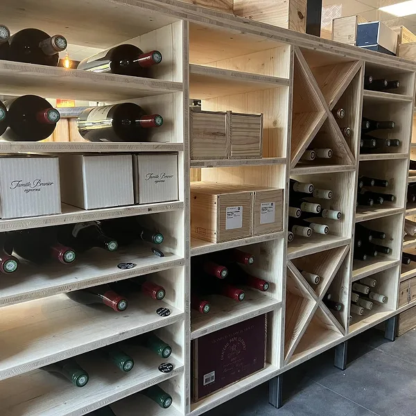 Étagères en bois avec bouteilles de vin couchées et caisses en bois dans une cave à vin.